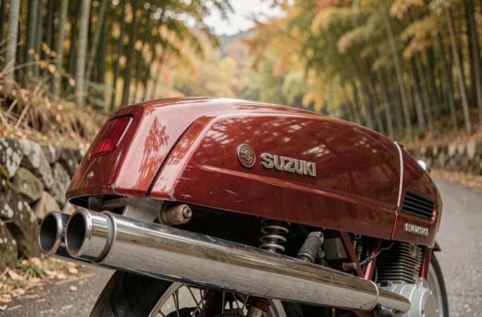 Suzuki GT750 rouge cerise années 1970 photographiée de trois quarts arrière sur une route de campagne japonaise